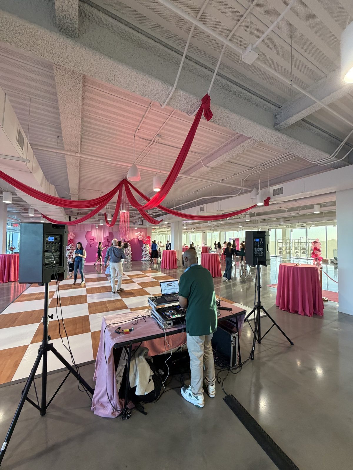 View from behind DJ D. Sewell’s booth over a pink-themed reception venue and dance floor